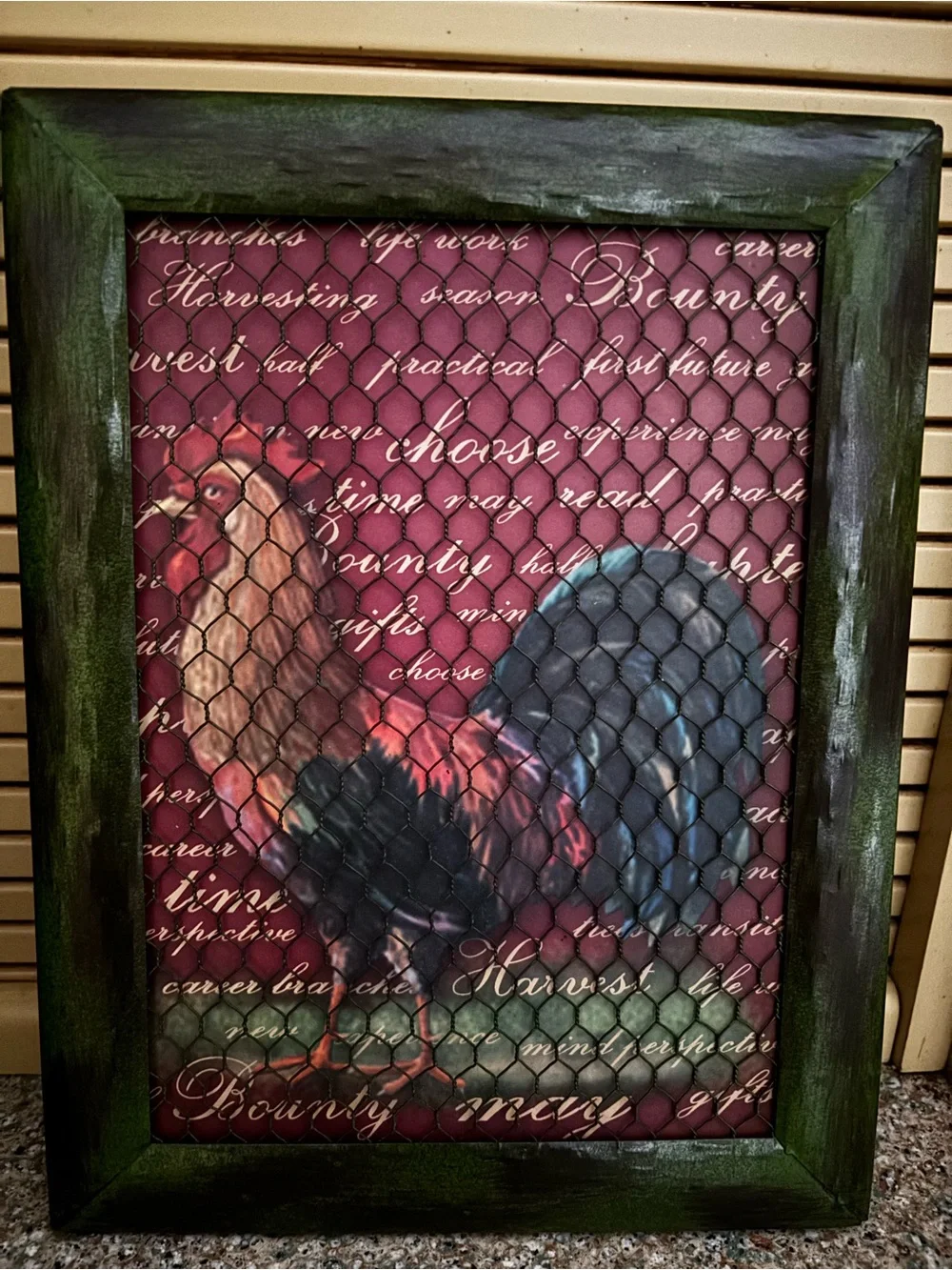 Rooster a rustic framed wall art piece behind chicken wire mesh.